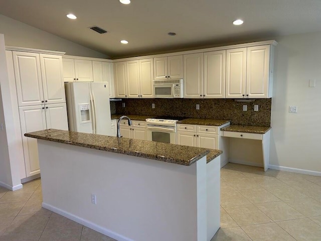 kitchen featuring white appliances, a center island with sink, white cabinetry, and vaulted ceiling