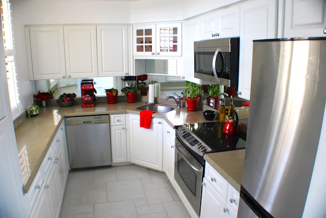 kitchen with light tile floors, white cabinets, and stainless steel appliances