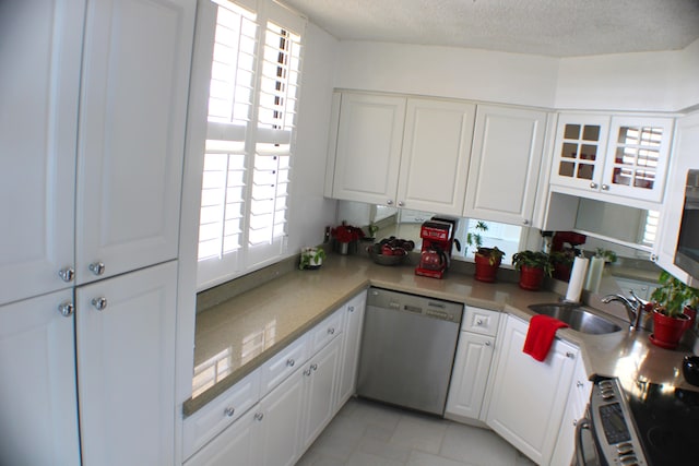 kitchen featuring appliances with stainless steel finishes, white cabinetry, light tile floors, a textured ceiling, and sink