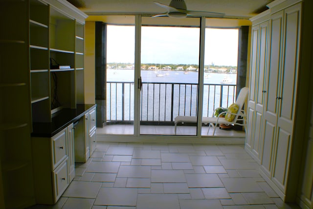 kitchen with white cabinets, a water view, light tile flooring, and ceiling fan