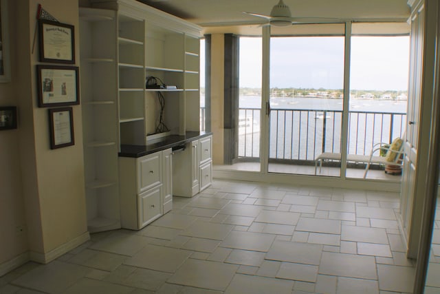 unfurnished office featuring ceiling fan, light tile flooring, and a water view