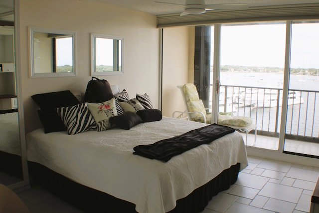 bedroom featuring a water view, access to exterior, ceiling fan, and light tile floors