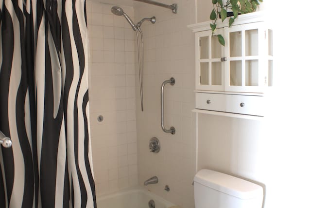 bathroom featuring toilet and shower / tub combo with curtain