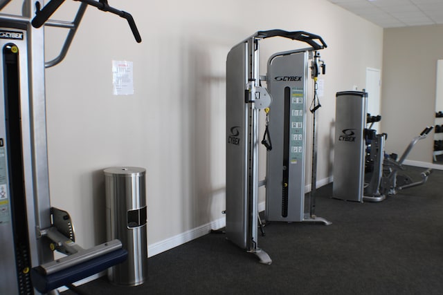 workout area with a drop ceiling and dark colored carpet