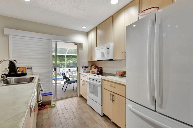 kitchen with light brown cabinetry, white appliances, sink, light hardwood / wood-style floors, and a textured ceiling