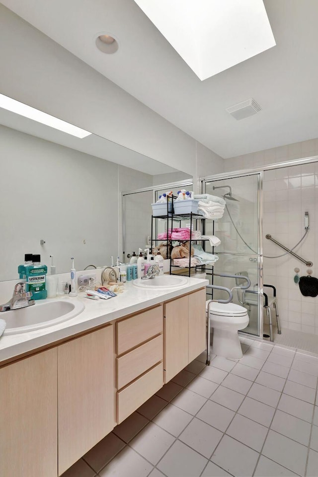 bathroom featuring a skylight, tile patterned flooring, toilet, and double sink vanity