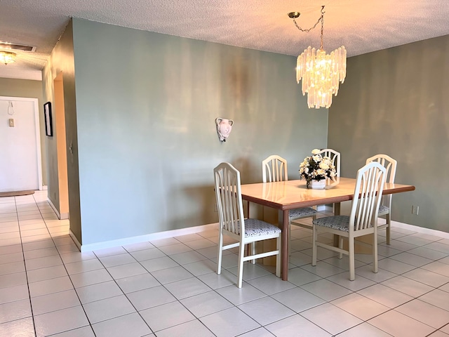 tiled dining area with a chandelier and a textured ceiling