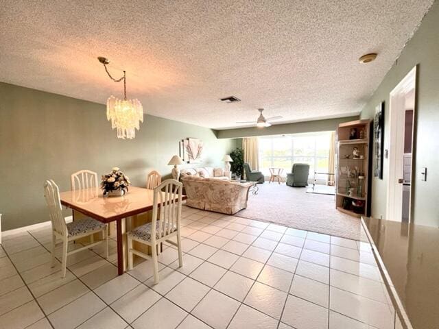 dining space with ceiling fan with notable chandelier, light tile patterned floors, and a textured ceiling