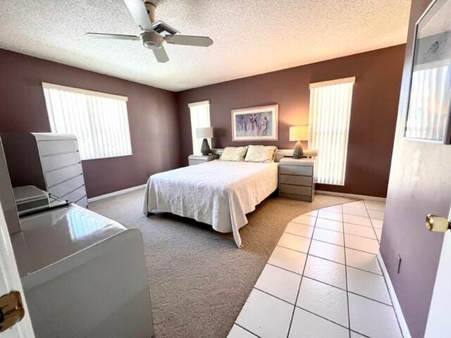 bedroom featuring light carpet, a textured ceiling, and ceiling fan