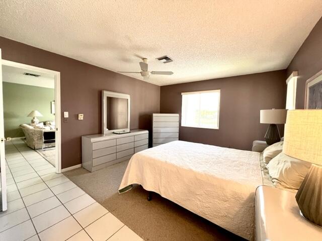 bedroom with light tile patterned floors, a textured ceiling, and ceiling fan