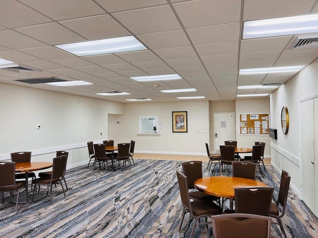 carpeted dining room with a paneled ceiling