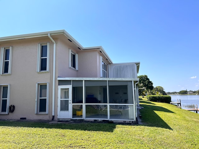 back of house with a sunroom, a yard, and a water view