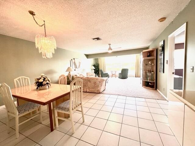 carpeted dining area with a textured ceiling and ceiling fan with notable chandelier