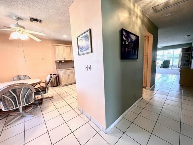 corridor featuring light tile patterned flooring and a textured ceiling