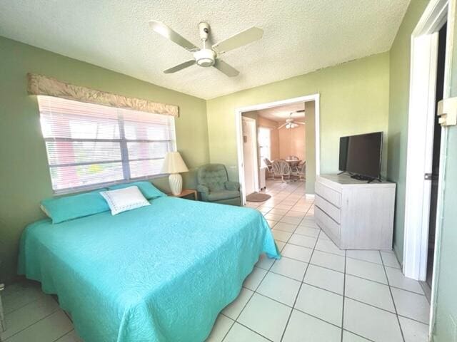 tiled bedroom with ceiling fan and a textured ceiling