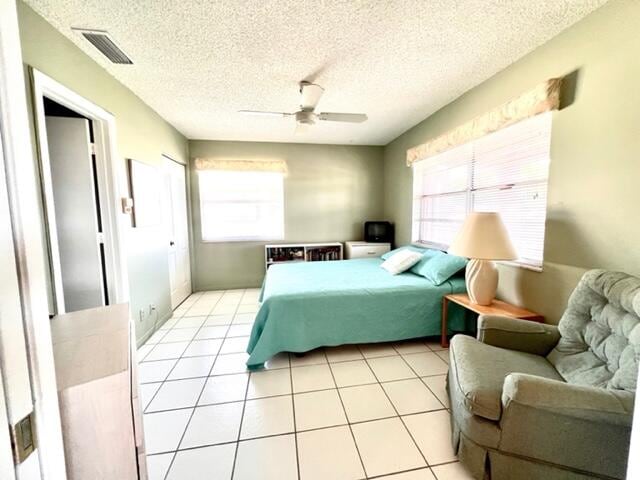 tiled bedroom featuring a textured ceiling and ceiling fan