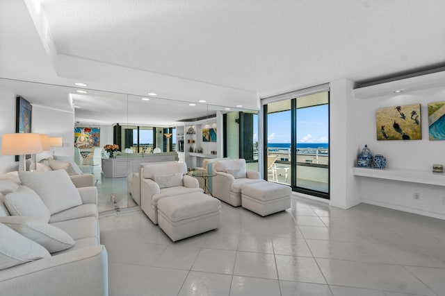 living room with a water view, floor to ceiling windows, and light tile floors