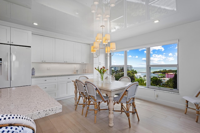 dining space featuring light hardwood / wood-style floors, an inviting chandelier, and a water view