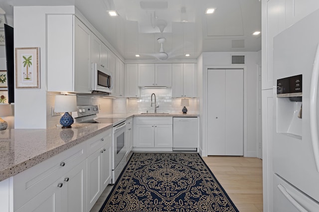 kitchen with light hardwood / wood-style flooring, sink, white cabinetry, light stone counters, and white appliances