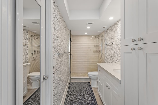 bathroom featuring toilet, a shower with shower door, and vanity