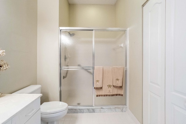 bathroom featuring tile patterned floors, vanity, toilet, and a shower with door