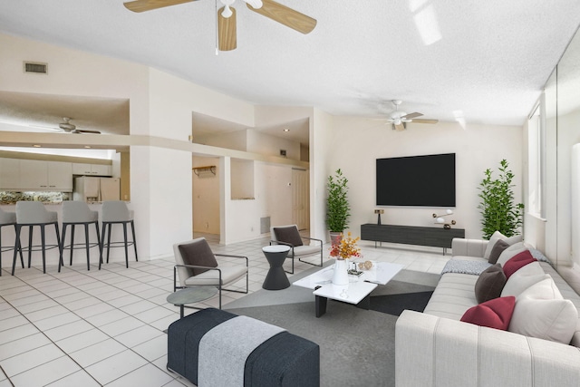 living room featuring ceiling fan, a textured ceiling, vaulted ceiling, and light tile patterned flooring