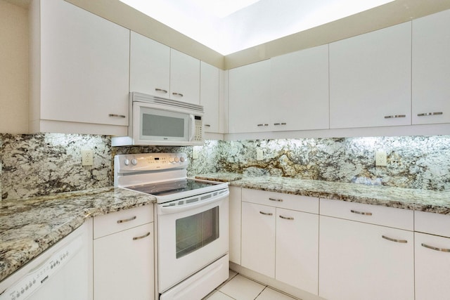 kitchen with white cabinetry, light stone countertops, light tile patterned floors, white appliances, and decorative backsplash