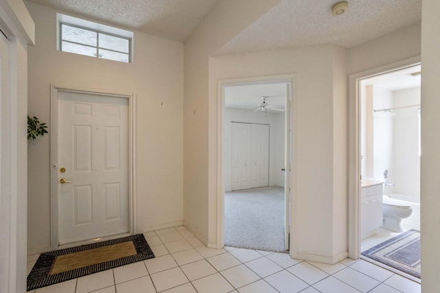 entrance foyer featuring ceiling fan, a textured ceiling, and light tile patterned floors