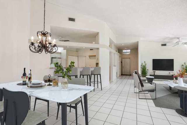 dining area with light tile patterned flooring, ceiling fan with notable chandelier, a textured ceiling, and vaulted ceiling