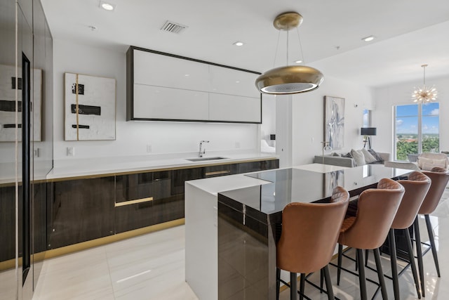 kitchen featuring sink, a breakfast bar, white cabinets, light tile patterned flooring, and hanging light fixtures