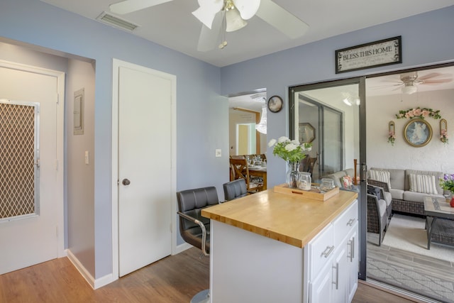 kitchen with light wood-type flooring, ceiling fan, and white cabinets