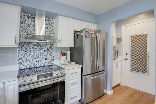 kitchen featuring stainless steel appliances, backsplash, wall chimney range hood, and white cabinetry