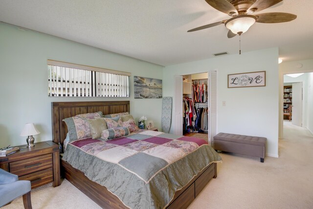 bedroom with a spacious closet, ceiling fan, light colored carpet, and a closet