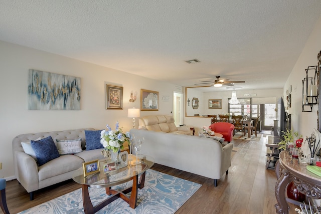 living room featuring hardwood / wood-style flooring, ceiling fan, and a textured ceiling