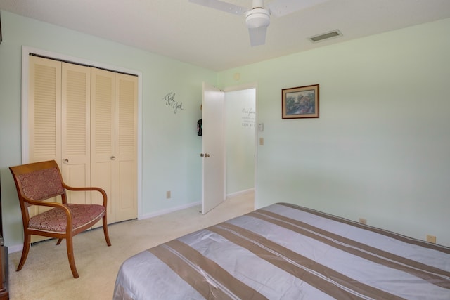 bedroom with ceiling fan, light colored carpet, and a closet