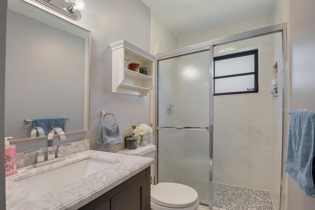 bathroom featuring vanity, a shower with shower door, and toilet