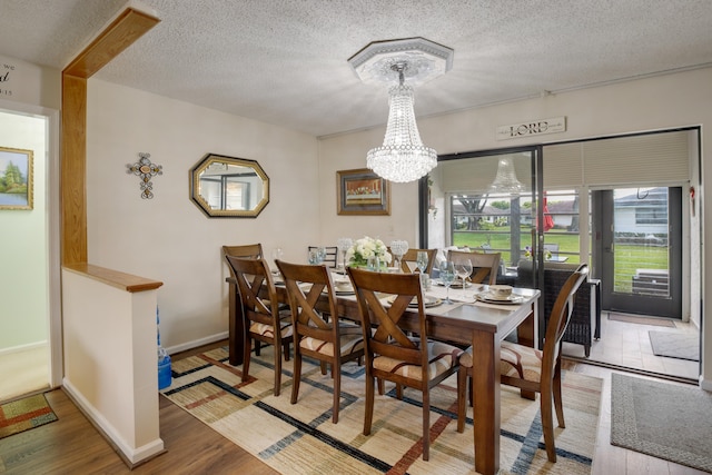 dining room with a textured ceiling, a chandelier, and hardwood / wood-style floors