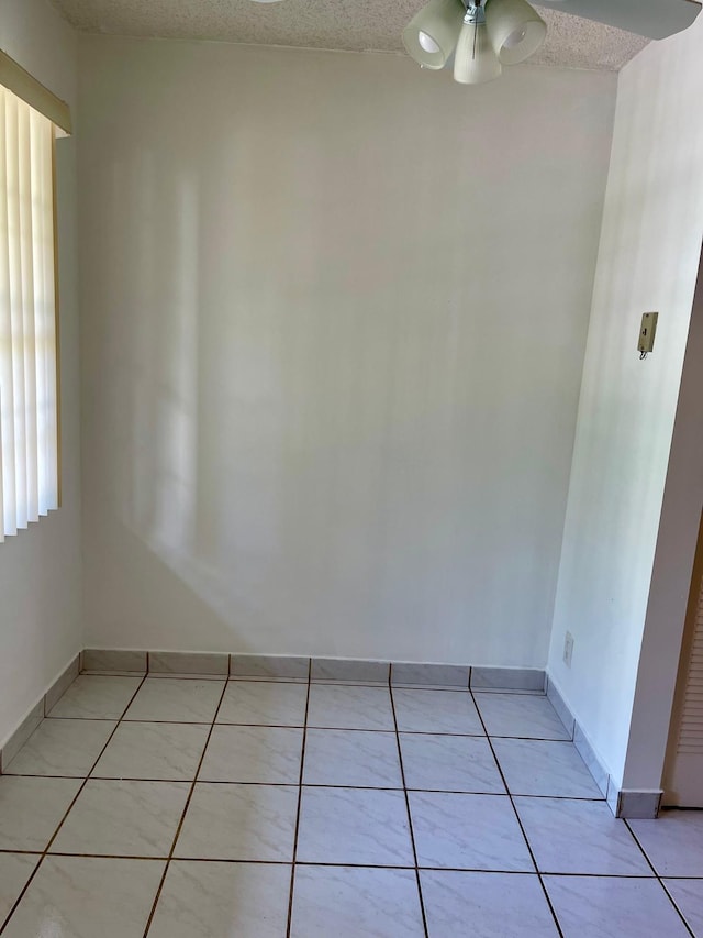 tiled spare room with ceiling fan and a textured ceiling