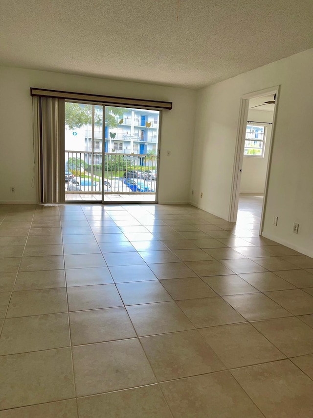 tiled empty room featuring a textured ceiling