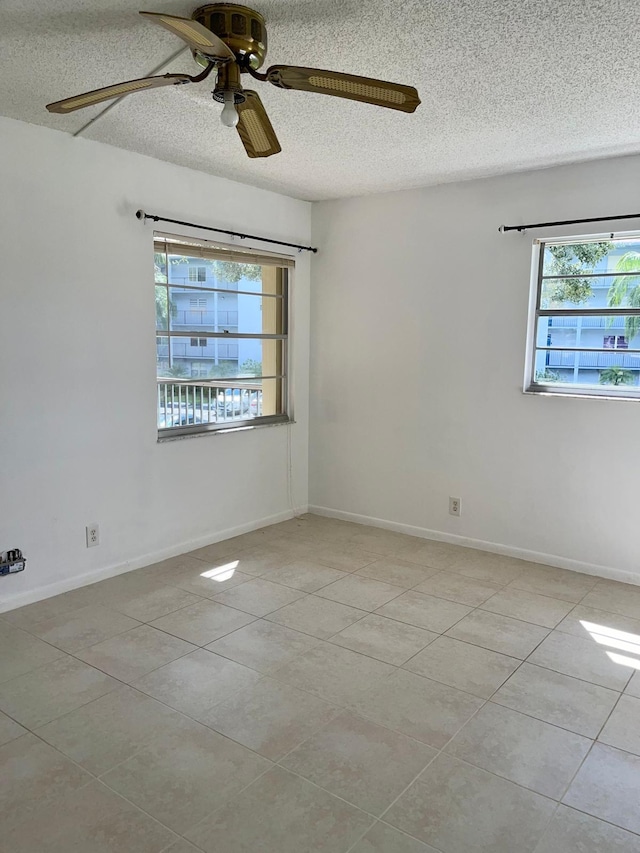 tiled spare room with ceiling fan, a healthy amount of sunlight, and a textured ceiling