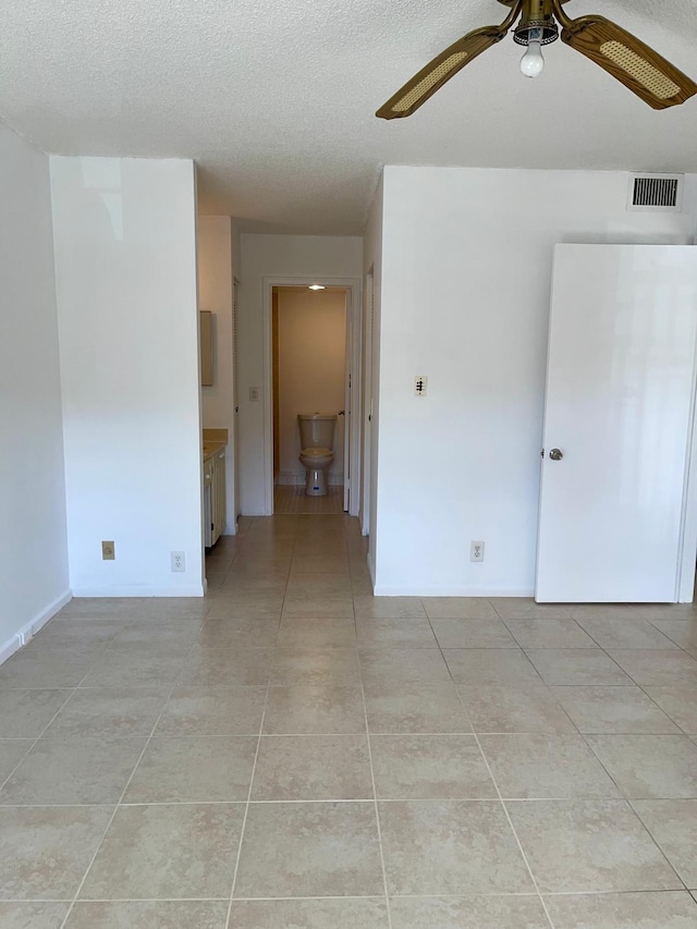 tiled empty room with ceiling fan and a textured ceiling