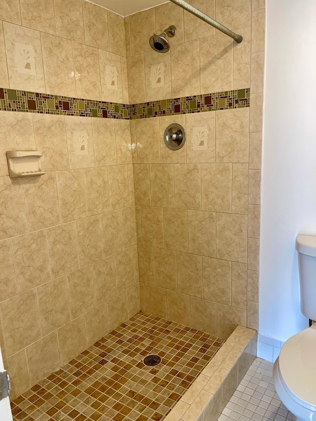 bathroom with tile patterned floors, toilet, and tiled shower