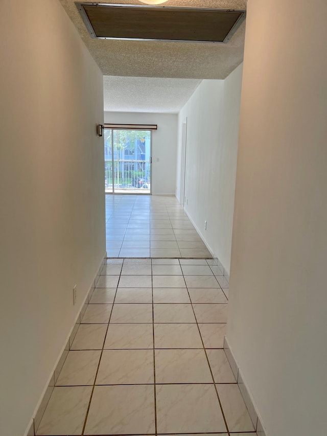 corridor featuring a textured ceiling and light tile patterned flooring