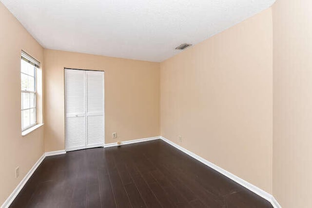 unfurnished bedroom with a closet and dark wood-type flooring