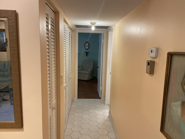 corridor featuring a textured ceiling and light tile patterned floors