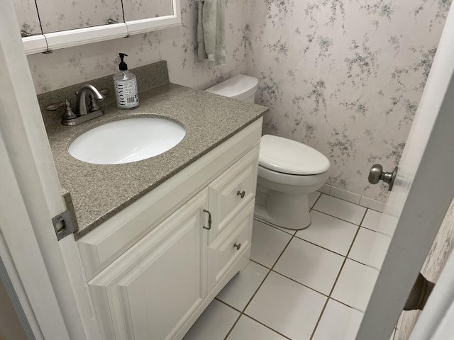 bathroom with toilet, vanity, and tile patterned flooring