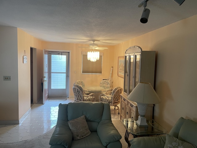 living room with a textured ceiling, ceiling fan, and light tile patterned floors