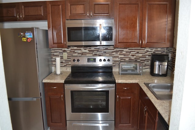 kitchen with backsplash, appliances with stainless steel finishes, and sink