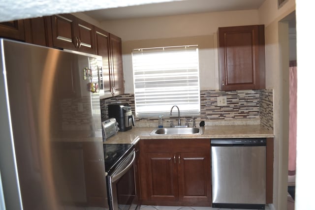 kitchen with appliances with stainless steel finishes, tasteful backsplash, dark brown cabinets, sink, and light tile flooring