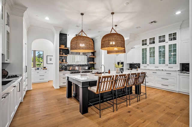 kitchen with pendant lighting, a center island with sink, white cabinetry, and a kitchen breakfast bar